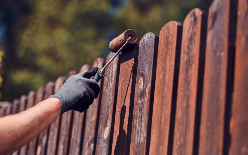 man-protective-gloves-is-painting-wooden-fence-bright-summer-day (1)